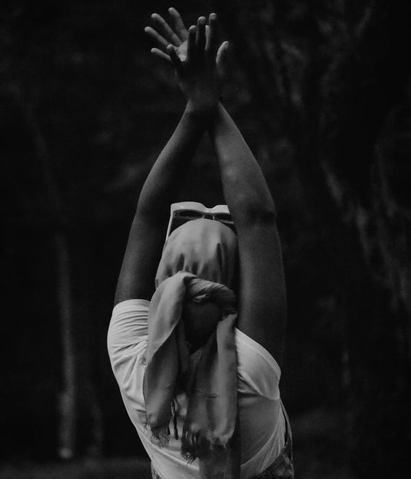 Woman in a calm yoga pose against a dark background with a cranberry accent.